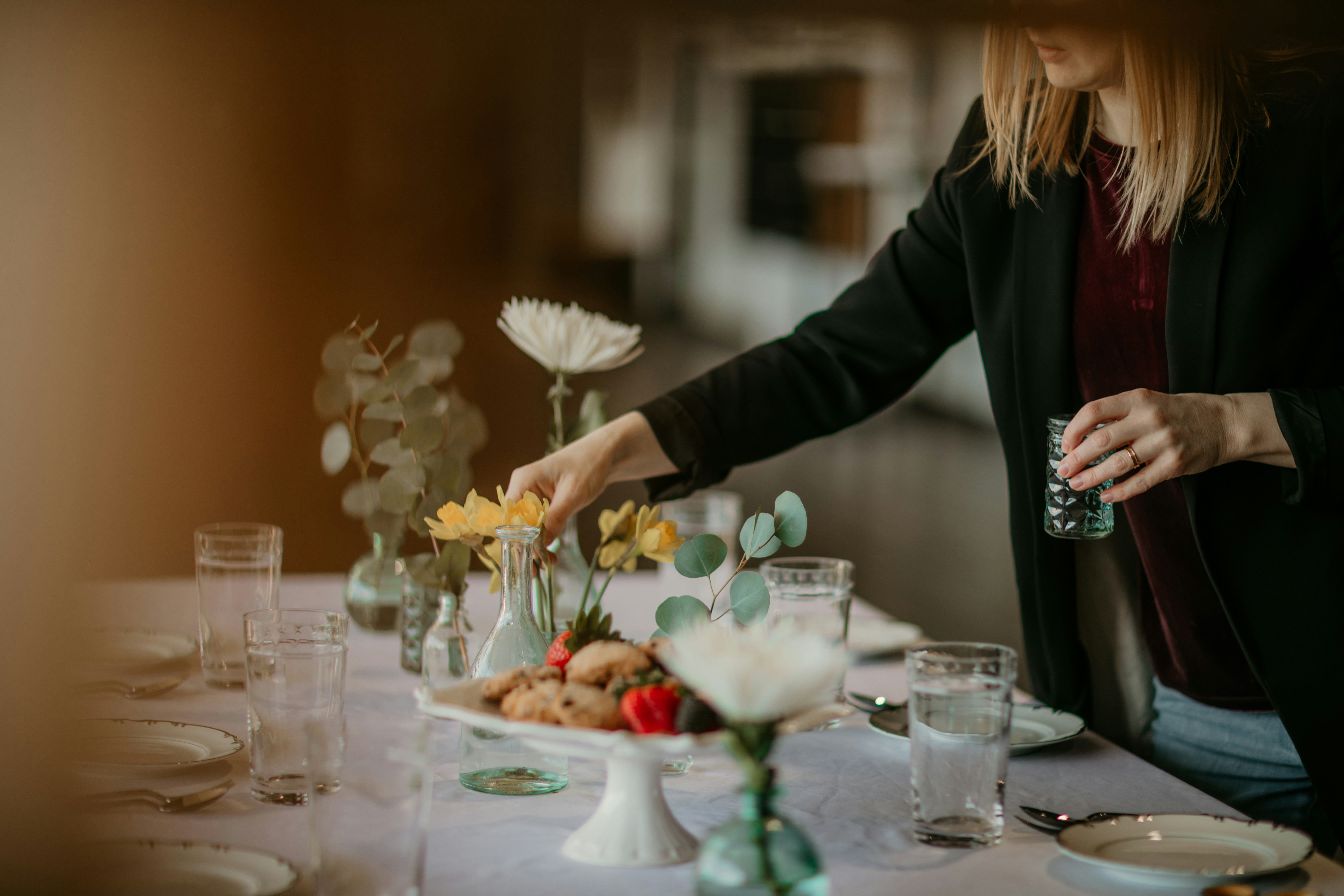 Event planner arranging floral centrepieces on an elegantly set table