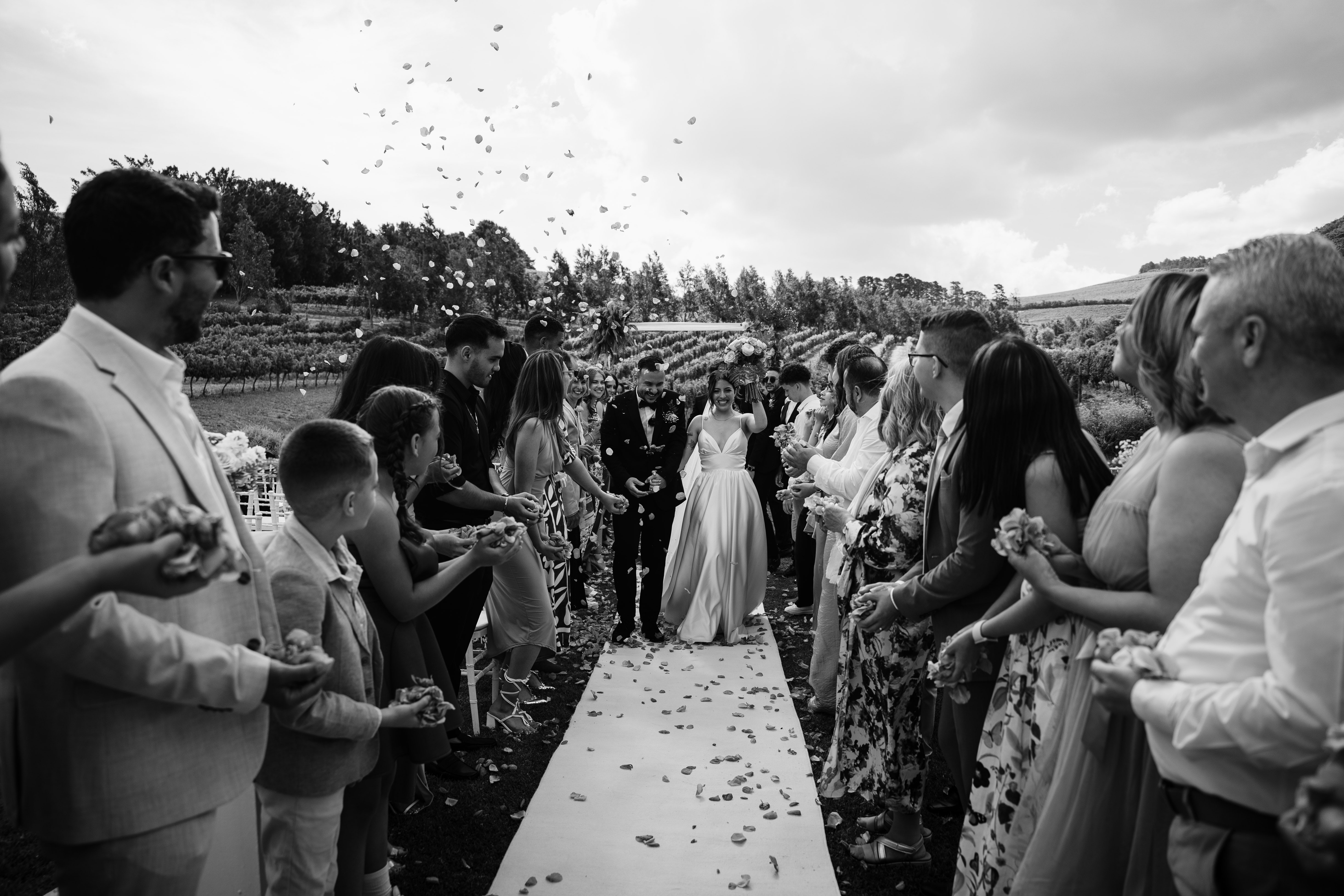 Bride and groom walking down the aisle as guests throw confetti at a Cape Winelands wedding