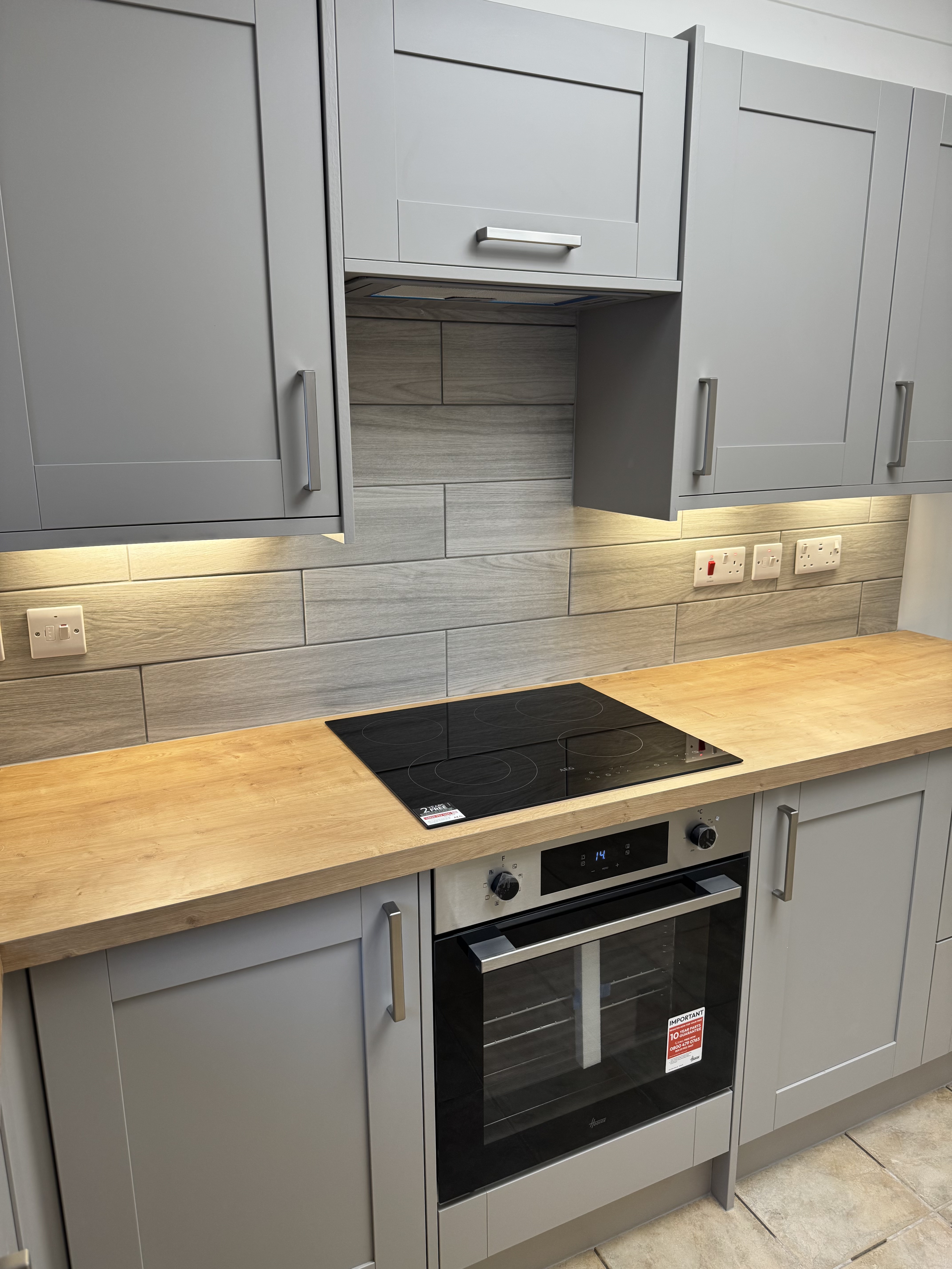 Grey shaker kitchen with oak worktop, under-cabinet LED lighting and integrated hob