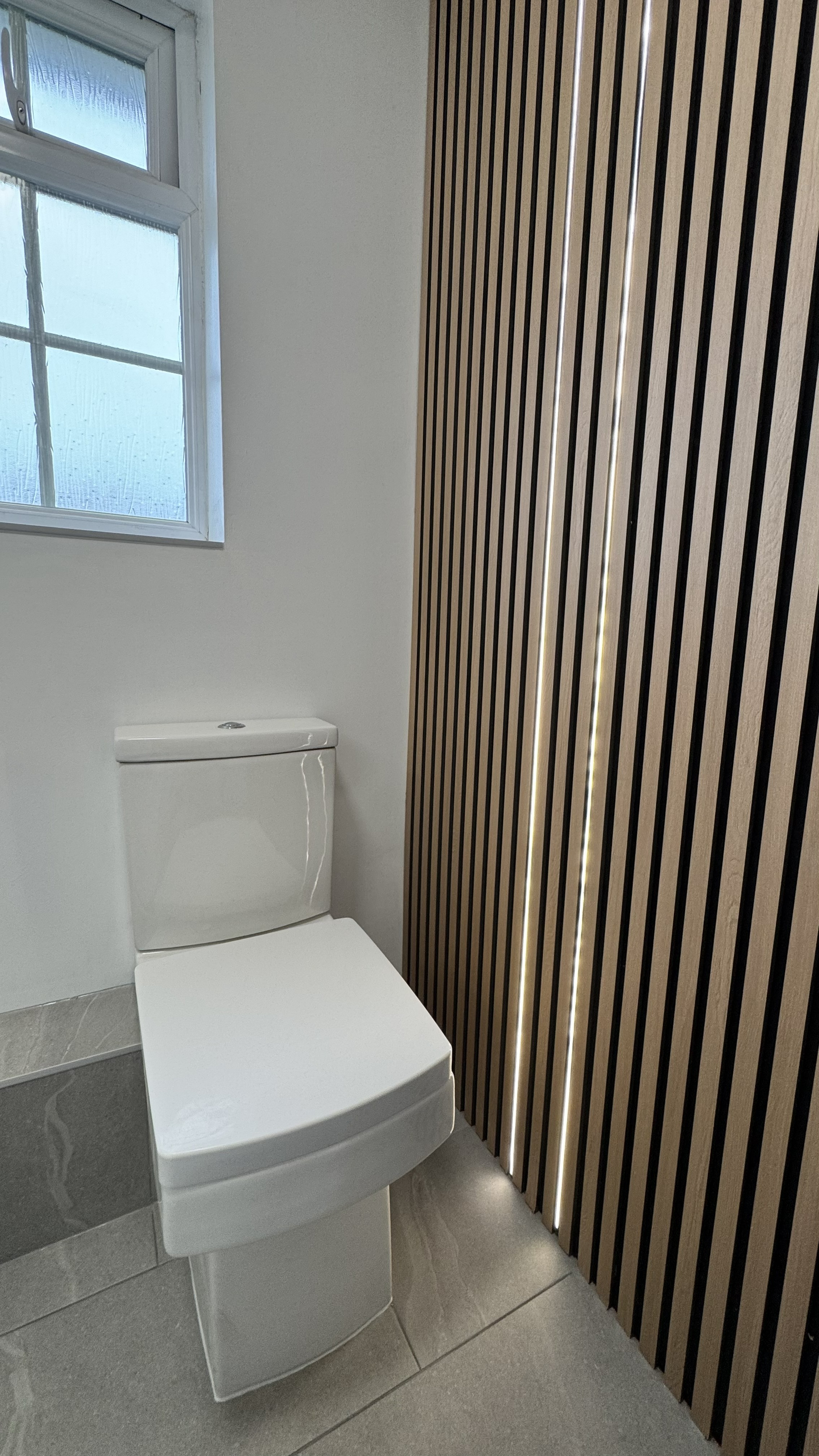 Oak slat feature wall with integrated LED lighting behind toilet — Bournemouth bathroom