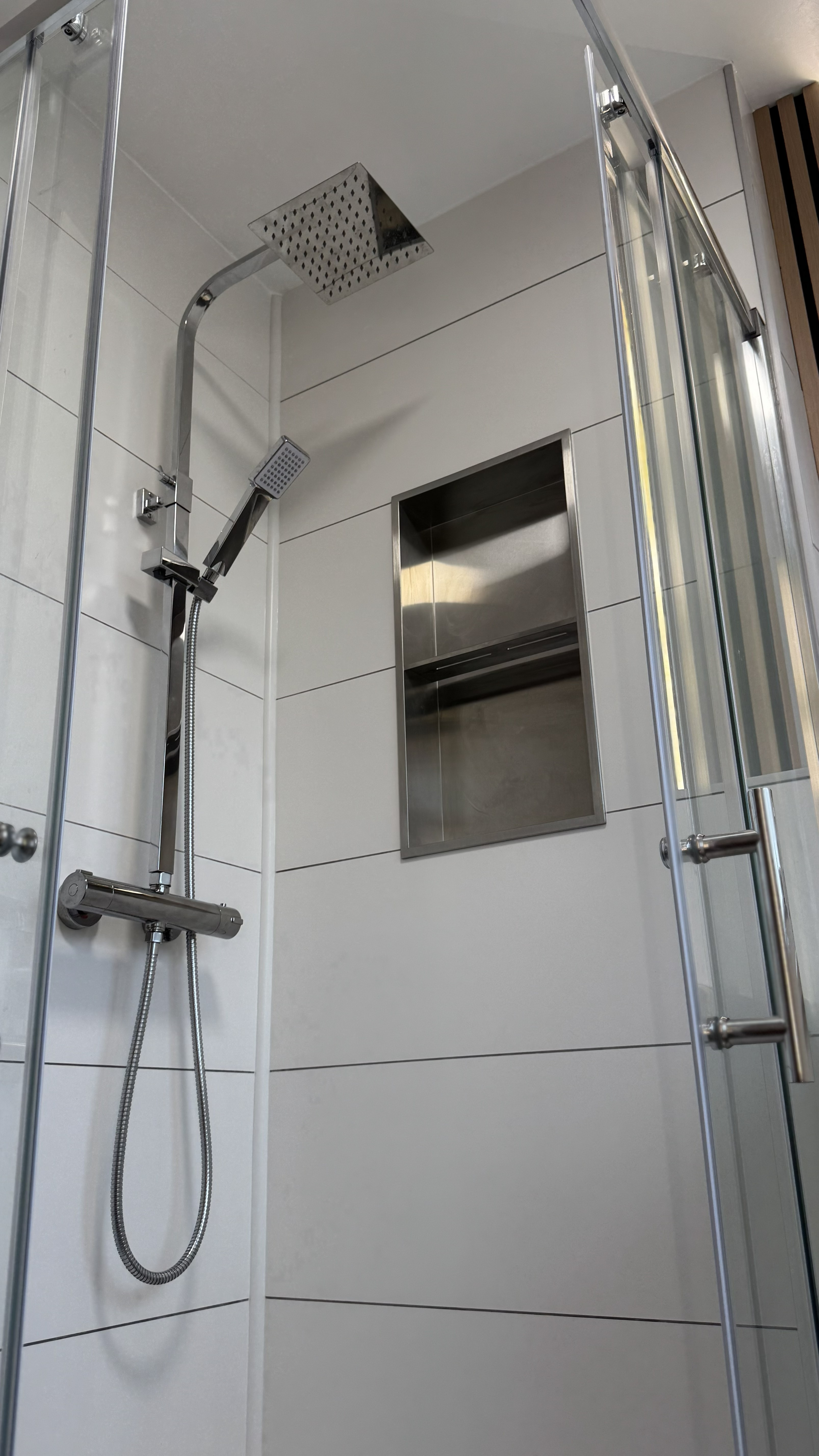 Frameless walk-in shower with rainfall head, handheld shower, and stainless steel niche — Bournemouth bathroom renovation