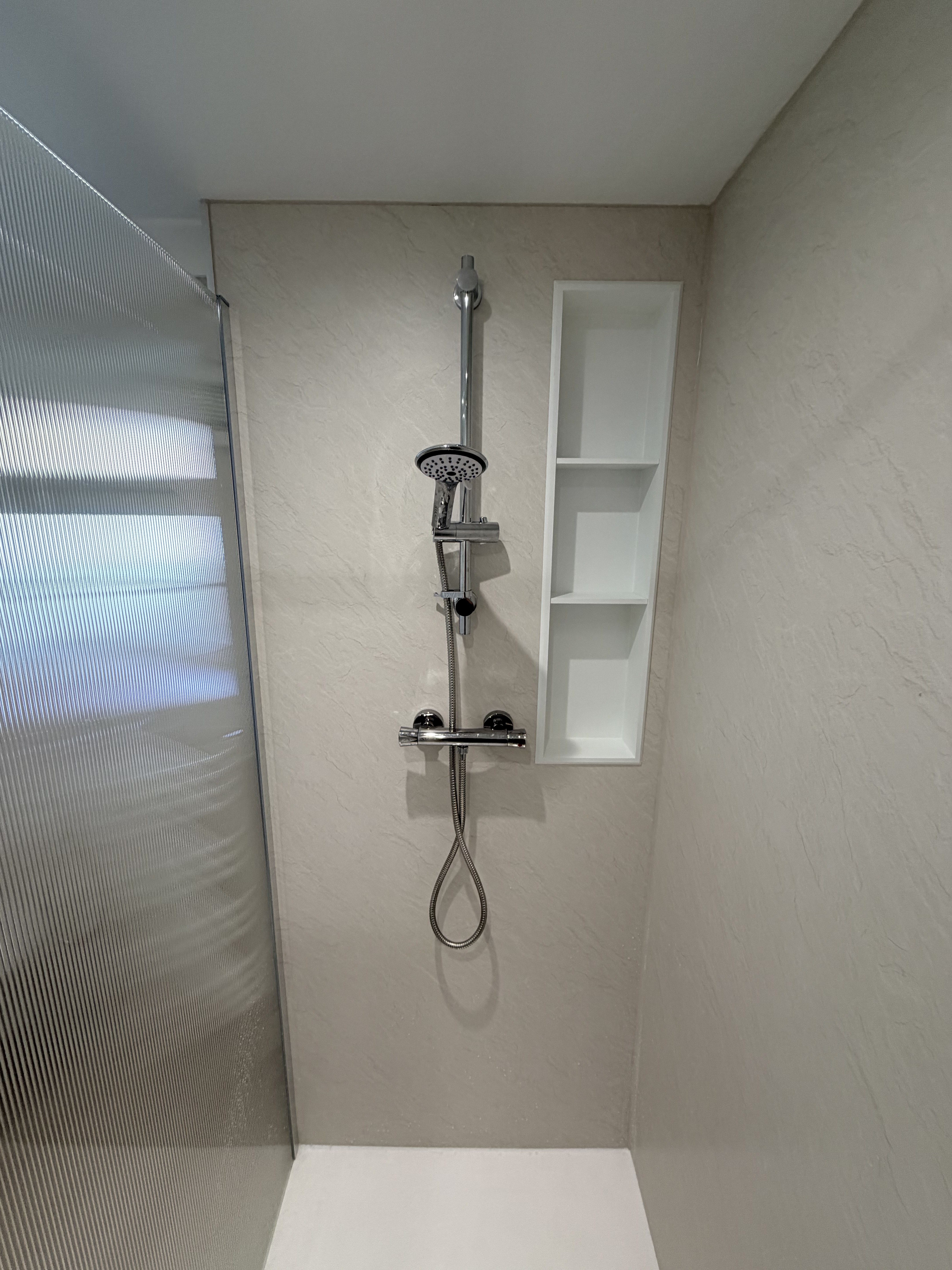 Walk-in shower interior — stone-effect panels, thermostatic shower and recessed niche shelving — Bearwood