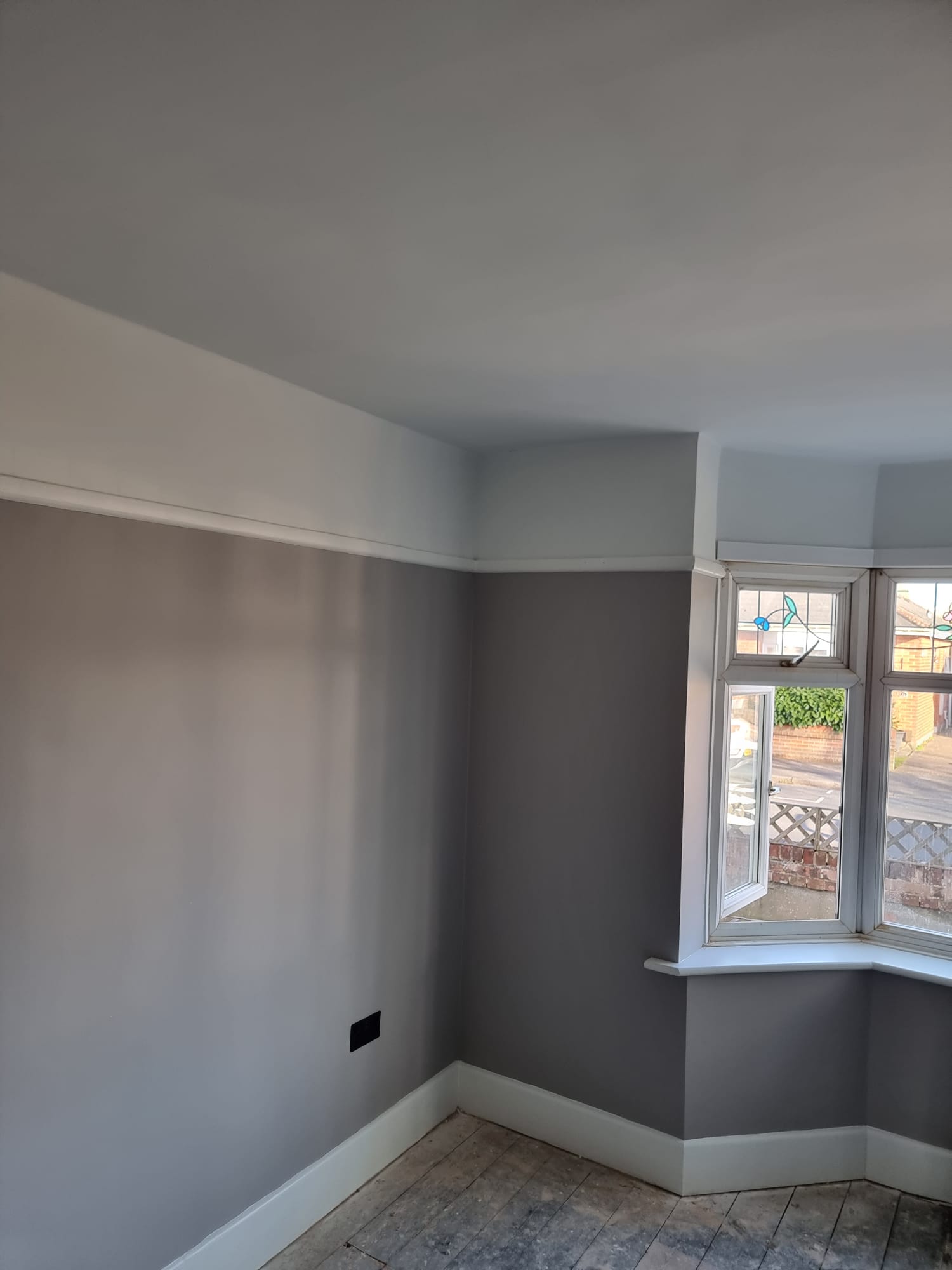Smooth grey painted room with clean white skirting and bay window — professional finish