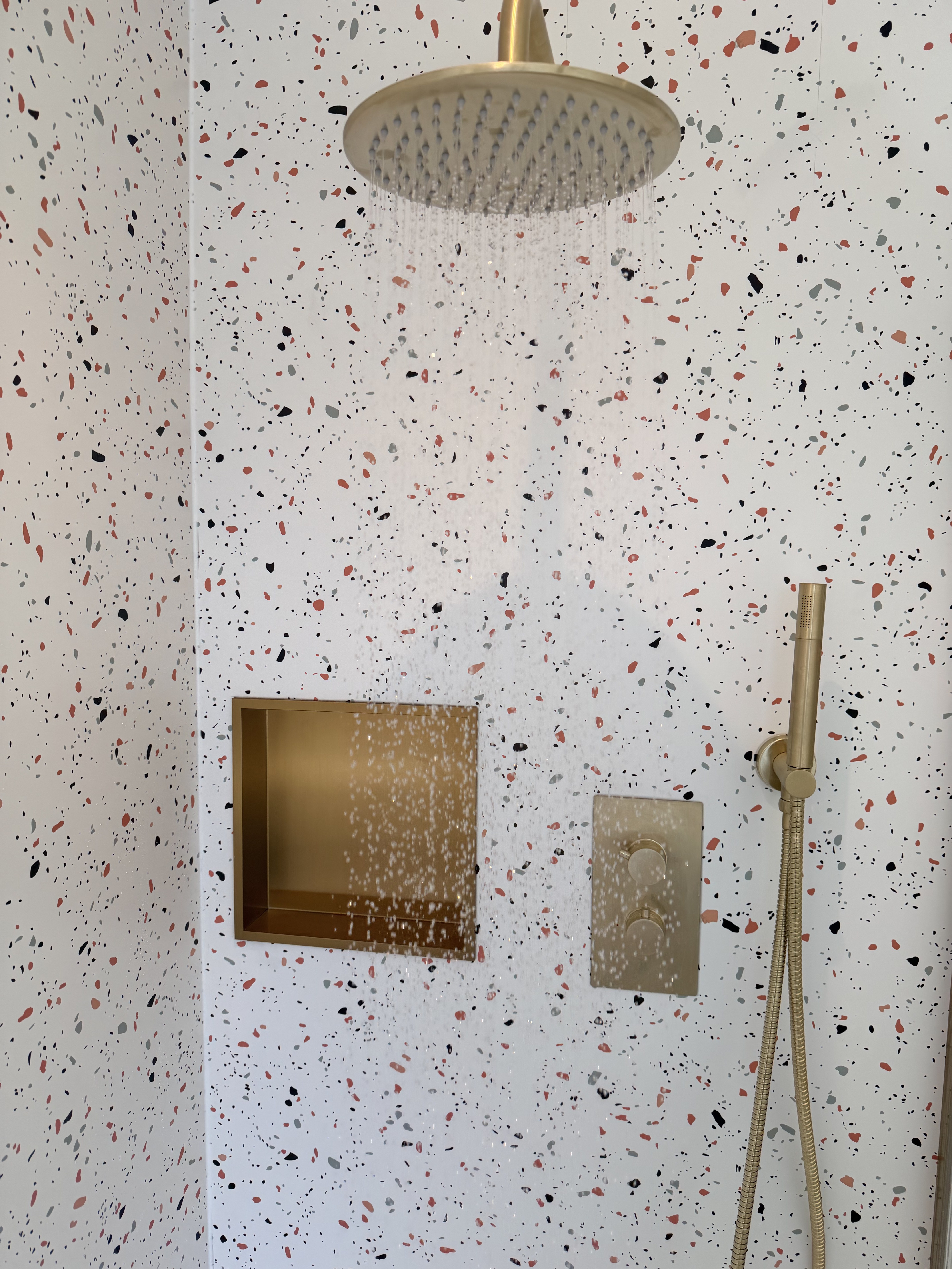 Shower detail — terrazzo tiles, brushed brass rainfall head and recessed niche — Charminster bathroom