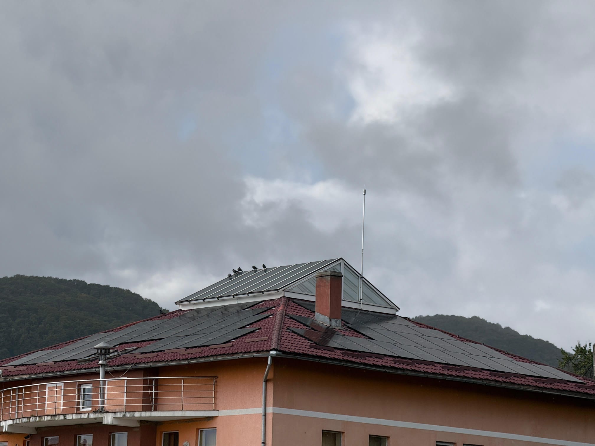 Detaliu acoperis Primaria Coroieni cu panouri fotovoltaice full-black si dealuri in fundal