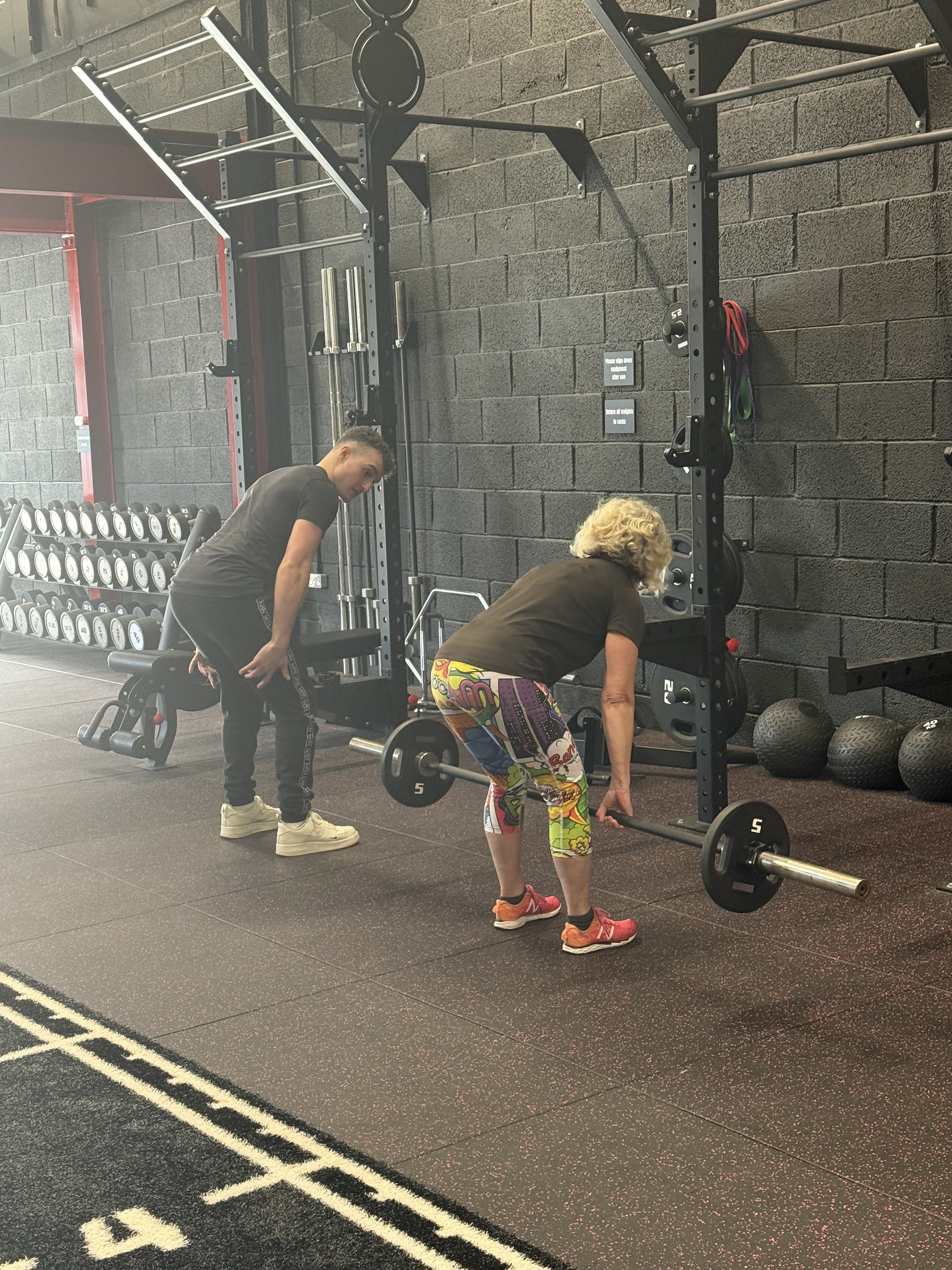 Personal trainer coaching a member on barbell technique