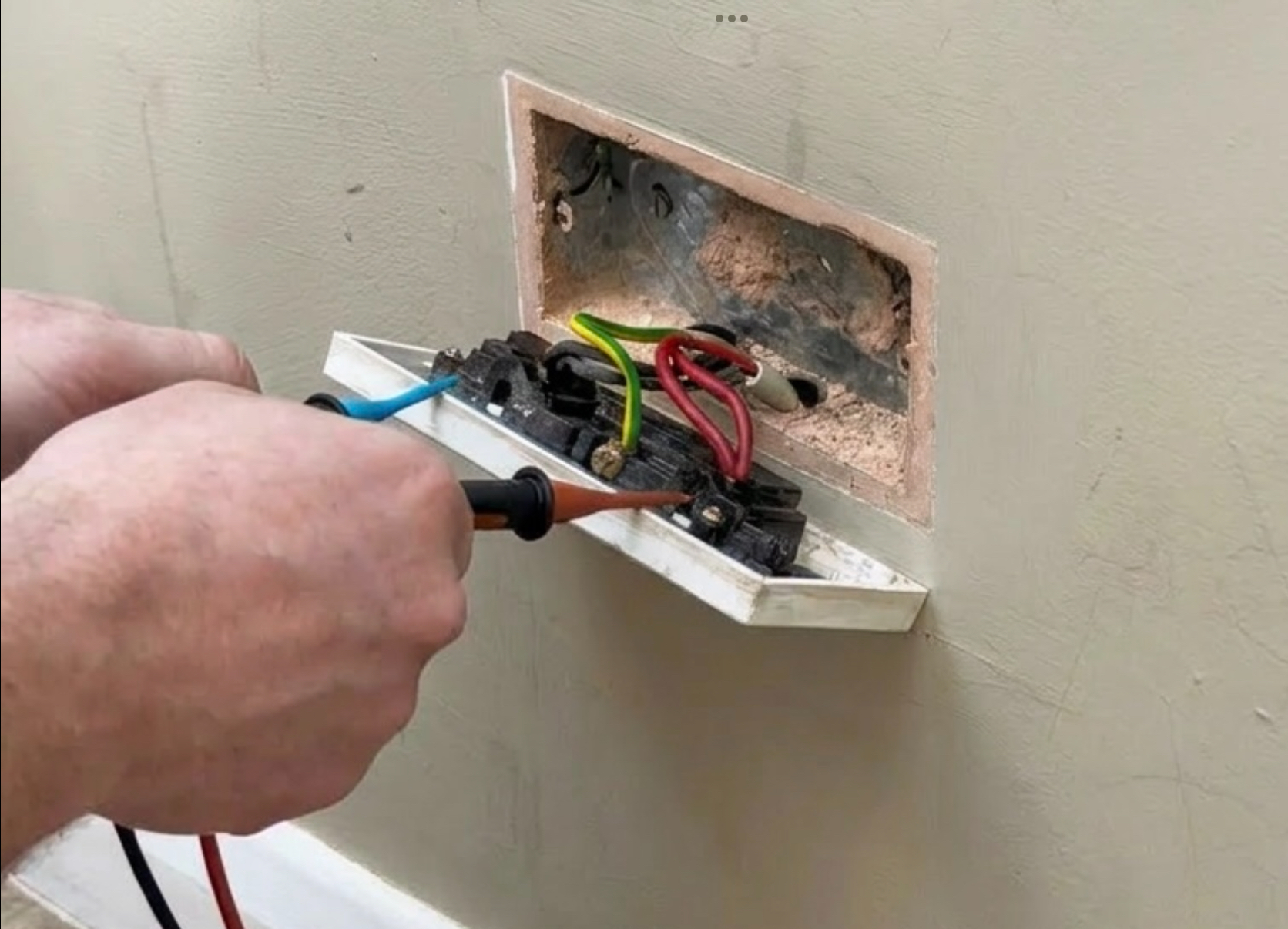 Severely burned electrical back box being tested during EICR, dangerous wiring fault found by Power Team Electrics
