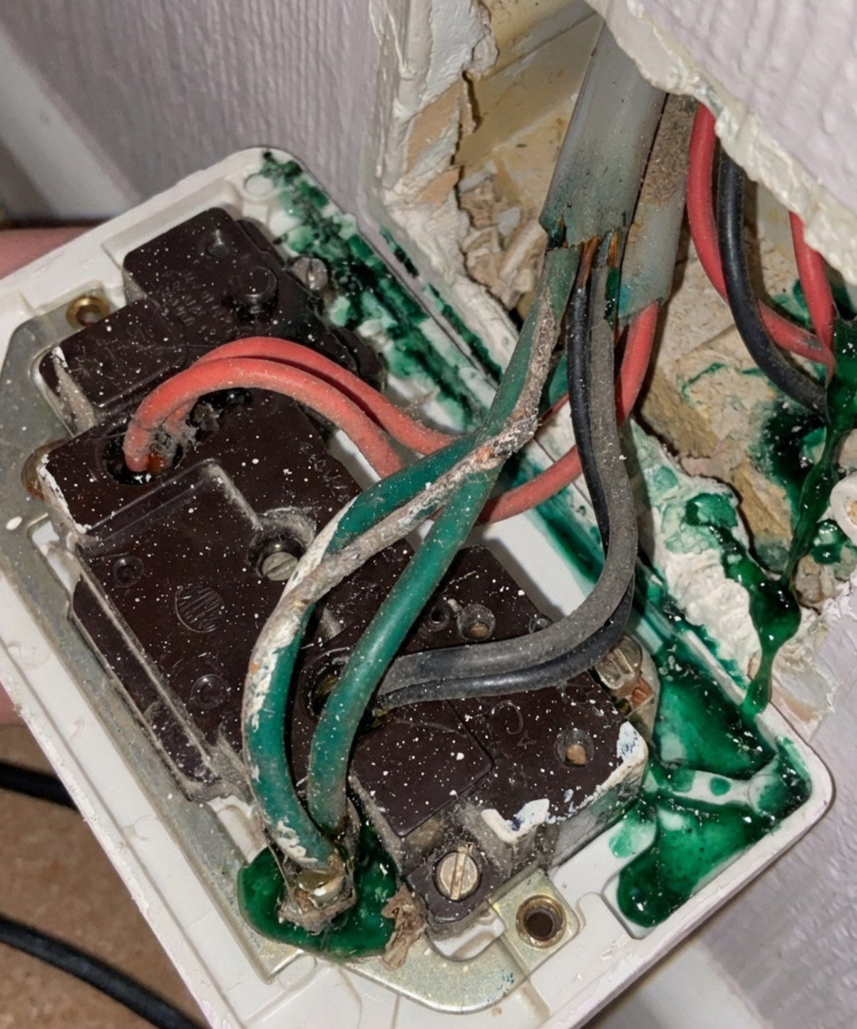 Severely degraded electrical socket with green corrosion on old rubber-insulated wiring found during EICR inspection