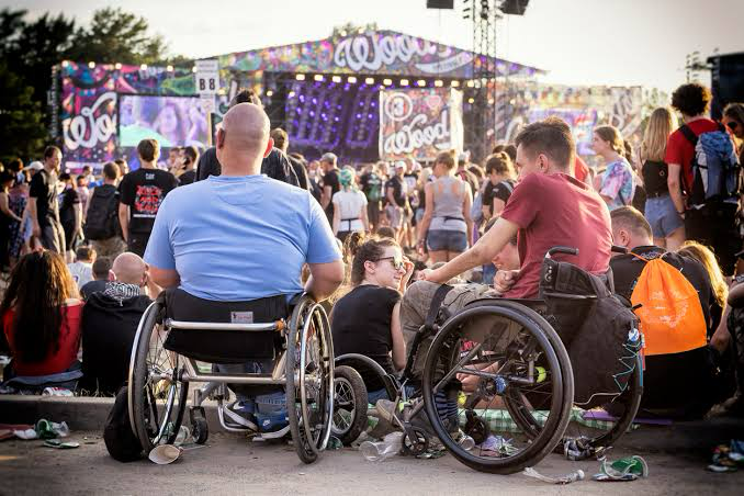 Steward welcoming wheelchair user through accessible entrance at a UK events venue