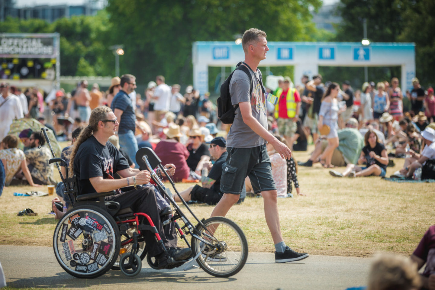 Steward welcoming wheelchair user through accessible gate at a UK outdoor music festival